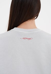 Ljusgrå sweatshirt med rund halsringning. Har en liten röd broderad logotyp på baksidan. Tillverkad av bomull med en mjuk känsla.