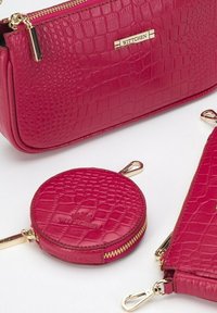 Accessori in pelle con texture a coccodrillo rosa, tra cui un borsellino con zip, un portamonete rotondo di piccole dimensioni e un portafoglio piatto con dettagli in oro.