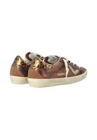 Une paire de baskets basses marron avec des lacets blanc cassé, des accents en imprimé léopard sur les talons et des semelles blanches texturées, inclinées pour montrer les dos et les côtés.