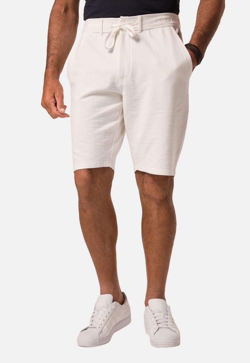 Shorts blancs texturés avec une taille élastique et un cordon de serrage, dotés de poches latérales et d'une coupe décontractée, associés à des baskets blanches.