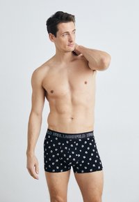 Fekete boxer alsónadrág, ismétlődő fehér mintával. Rugalmas derékpántján a "KARL LAGERFELD" felirat olvasható vastag betűkkel. Puha anyagú.
