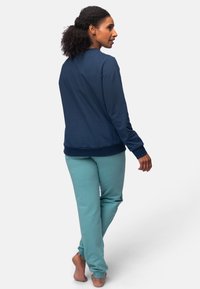 Marineblauwe crewneck sweater met ribgebreide manchetten, gecombineerd met licht turquoise sweatpants. Katoenen stof, ontspannen pasvorm, eenvoudig ontwerp.