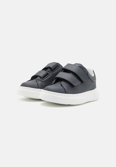 Mörkblå lädersneakers med två kardborreband, vita gummisulor och kontrasterande sömdetaljer. Rund tådesign.