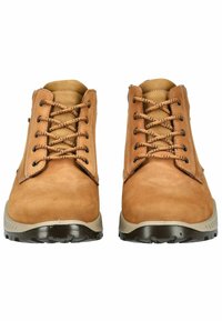 Stivaletti in suede marrone con lacci neri, punta rotonda e suola in gomma beige. Presentano cuciture rinforzate e occhielli per i lacci.