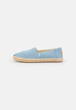 Jasnoniebieskie espadryle typu slip-on z plecioną juca, z małą metką tkaninową z boku, przedstawione w profilu na białym tle.
