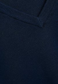 Maglione a maglia blu navy con scollo a V, polsini e corpo a costine testurizzati. Tessuto liscio con una trama uniforme in tutto il capo.