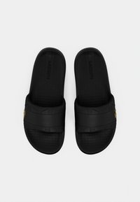 Μαύρα σανδάλια σφήνες από καουτσούκ με υφασμένα πέλματα και διπλούς ιμάντες. Διαθέτουν λεπτό χρυσό λογότυπο σε έναν ιμάντα. Απλός και πρακτικός σχεδιασμός.