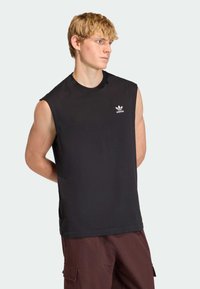 Čierne tielko bez rukávov z bavlny, s okrúhlym výstrihom a malým bielym logom Adidas na hrudi. Hladká textúra, športový strih.