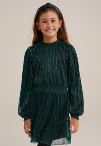 Vihreä poimutettu mekko pitkillä hihoilla, kuminauhamaisella vyötäröllä ja röyhelömäisellä helmalla. Viimeistelty pyöreällä pääntialla ja teksturoidulla, kiiltävällä kankaalla.