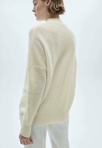 Maglione oversize color crema in maglia, con finitura texturizzata, spalle scese e orlo a coste. Design minimalista con vestibilità rilassata.