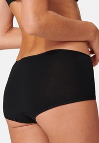 Zwarte katoenen slip met een gladde, naadloze ontwerp. Heeft een hoge taille en een zachte elastische band. Lichtgewicht stof met een licht doorschijnende uitstraling.