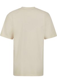 Bomulds T-shirt i lys beige, kortærmet, rund hals, glat tekstur, uden synlige mønstre eller grafik, enkelt design.