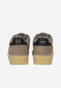 Bruine suède schoenen met een fuzzy grijze bovenkant, voorzien van een tan rubberen zool. Zwarte leren accenten op de hiel met gouden letters.