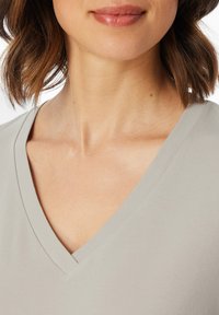 Light gray V-neck t-shirt made of smooth fabric, featuring a clean neckline and soft texture. The shirt covers the upper chest area.