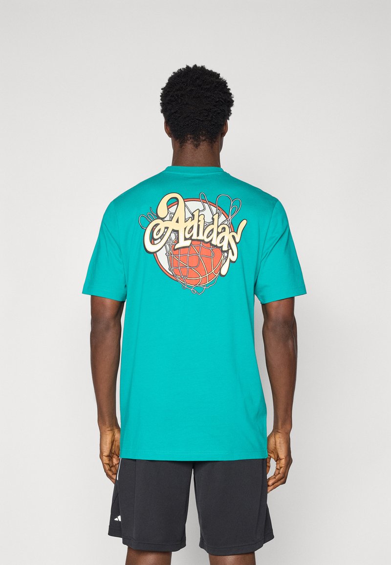 Tirkīza krāsas īsām piedurknēm T-krekls ar apaļu kakla izgriezumu. Aizmugurē ir liels retro stila Adidas logotips un basketbola grafika.