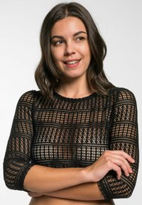 Schwarzes Spitzen-Crop-Top mit dreiviertelärmeln, filigranen Mustern, einem gewellten Ausschnitt und transparenter Textur.