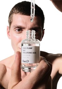 Bottiglia con contagocce in vetro trasparente etichettata "Acido Ialuronico Pure Plump HA4", contenente un liquido, tenuta in una mano, con il contagocce che distribuisce una goccia sopra.