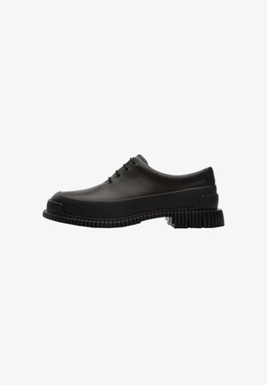 Black rubber shoes with a rounded toe and thick ridged sole. Features five eyelets for laces and smooth, glossy texture.