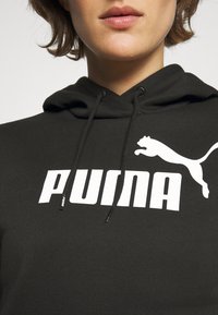 Felpa nera con cappuccio realizzata in tessuto morbido, con un grande logo bianco "PUMA" e un'immagine di un puma in corsa. Cordini regolabili per il cappuccio.