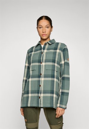 Green and cream plaid flannel shirt with a collar, front buttons, two chest pockets, and a subtle logo patch on the sleeve.