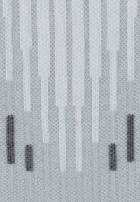 Tessuto lavorato a maglia grigio chiaro con motivi rettangolari verticali bianchi e grigio scuro che somigliano a tronchi d'albero astratti.