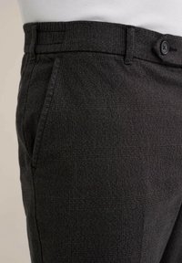 Randiga byxor i mörkgrått tyg, med standard midja, knäppning och sidofickor. Strukturerat material med subtila mönster.