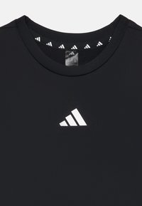 Black athletic t-shirt made of smooth fabric with a round neckline and white triangular logo on the front, featuring a patterned inner collar.