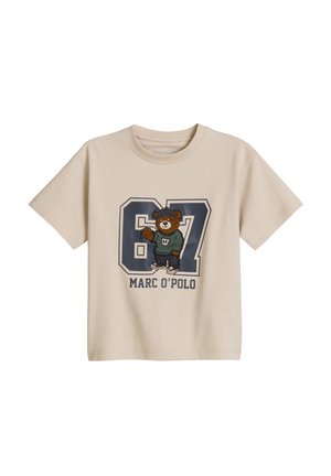 T-shirt beige à manches courtes avec un grand numéro 87, un ours portant un pull vert et des baskets, et le texte "Marc O'Polo" sur le devant.