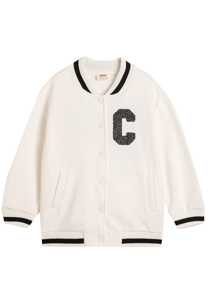 Hvid varsity-jakke lavet af blødt stof. Har et sort glitrende "C" patch, ribbet krave, manchetter og nederkant med sorte striber. To sidelommer.