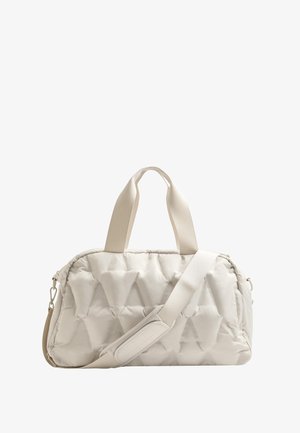 Párnázott bézs sporttáska steppelt mintázattal. Két fogantyúval és levehető vállpánttal rendelkezik, amely párnázott részleteket tartalmaz a kényelem érdekében.