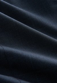 Navy textiel met een subtiel roosterpatroon, dat soepele plooien en een lichte glans vertoont. Geschikt voor op maat gemaakte kleding of tapijten.
