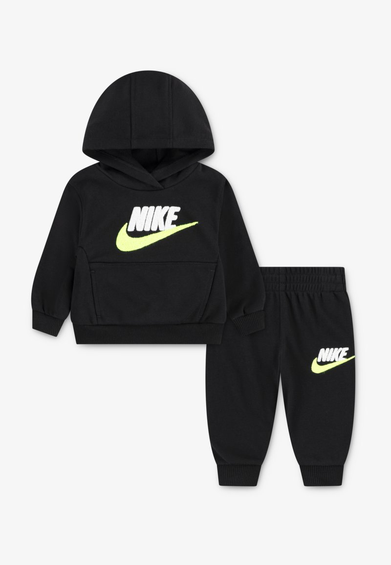 Fekete Nike kapucnispulóver elülső zsebbel és neon sárga logóval, összehangolt fekete jogger nadrággal, amelynek combján szintén megtalálható a logó.