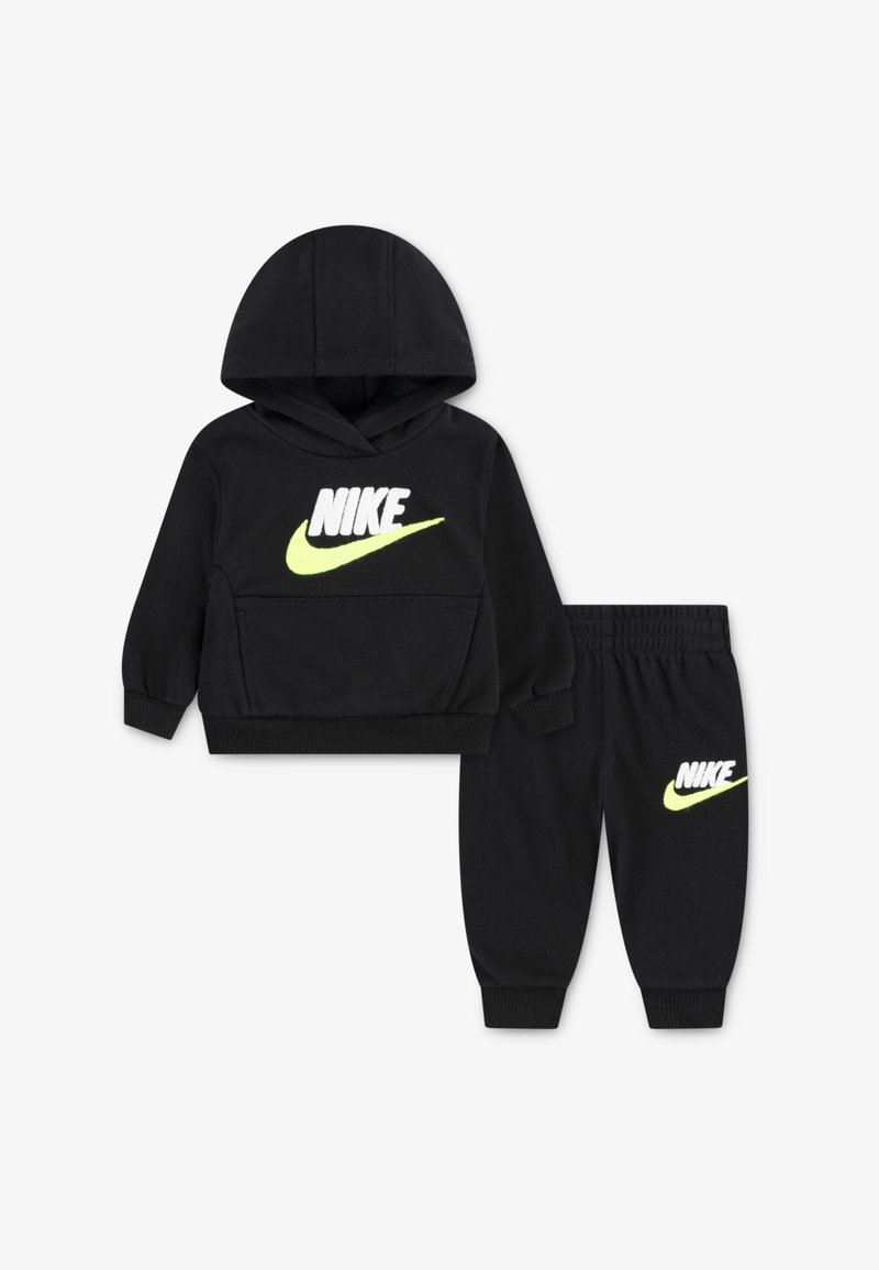 Schwarzer Nike-Hoodie mit einer Vordertasche und neongelber Logoplatzierung, kombiniert mit passenden schwarzen Jogginghosen, die dasselbe Logo am Oberschenkel tragen.