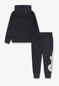 Ensemble de hoodie et de pantalon de survêtement bleu marine foncé, fabriqué en tissu doux, avec un grand motif blanc de personnage sur la jambe du pantalon et une capuche.