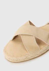 Bež espadrille sandaalid, millel on ületavad suède rihmad, pehme tekstuuriga pealispind ja köie detailid talla äärsel.