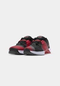 Røde og sorte sportssko med en mesh-overdel, teksturerede mønstre, snørebåndsindlæsning og en hvid slidstærk sål. Med Nike-branding på siderne.