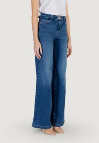Wide-leg blue denim jeans with a high waist, featuring a visible belt loop and a smooth texture. Hem is slightly flared at the bottom.
