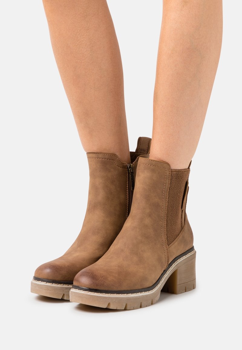 Braune, kunstlederne Stiefeletten mit einem dicken Absatz, elastischen Seitenpanels und einem Reißverschluss, ausgestattet mit einer strukturierten Oberfläche und einer stabilen Sohle.