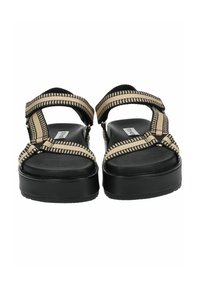 Sandali platform neri e beige con cinghie intrecciate, dotati di un plantare piatto e testurizzato e cinturini alla caviglia regolabili per una vestibilità sicura.