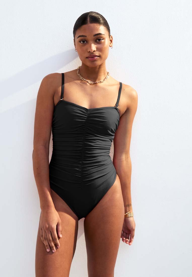 Bañador negro de una pieza con textura fruncida, tirantes delgados ajustables y un diseño de pierna alta. Tejido suave y construcción sencilla.