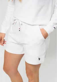 Witte katoenen shorts met een gestructureerd oppervlak, voorzien van zijzakken en een tailleband met koord in rood, wit en blauw. Zwart logo.