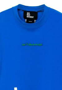 Camiseta de algodón azul con cuello redondo. Presenta un logotipo de texto verde "Obt Black Design" en el pecho y un acento blanco contrastante en el dobladillo.