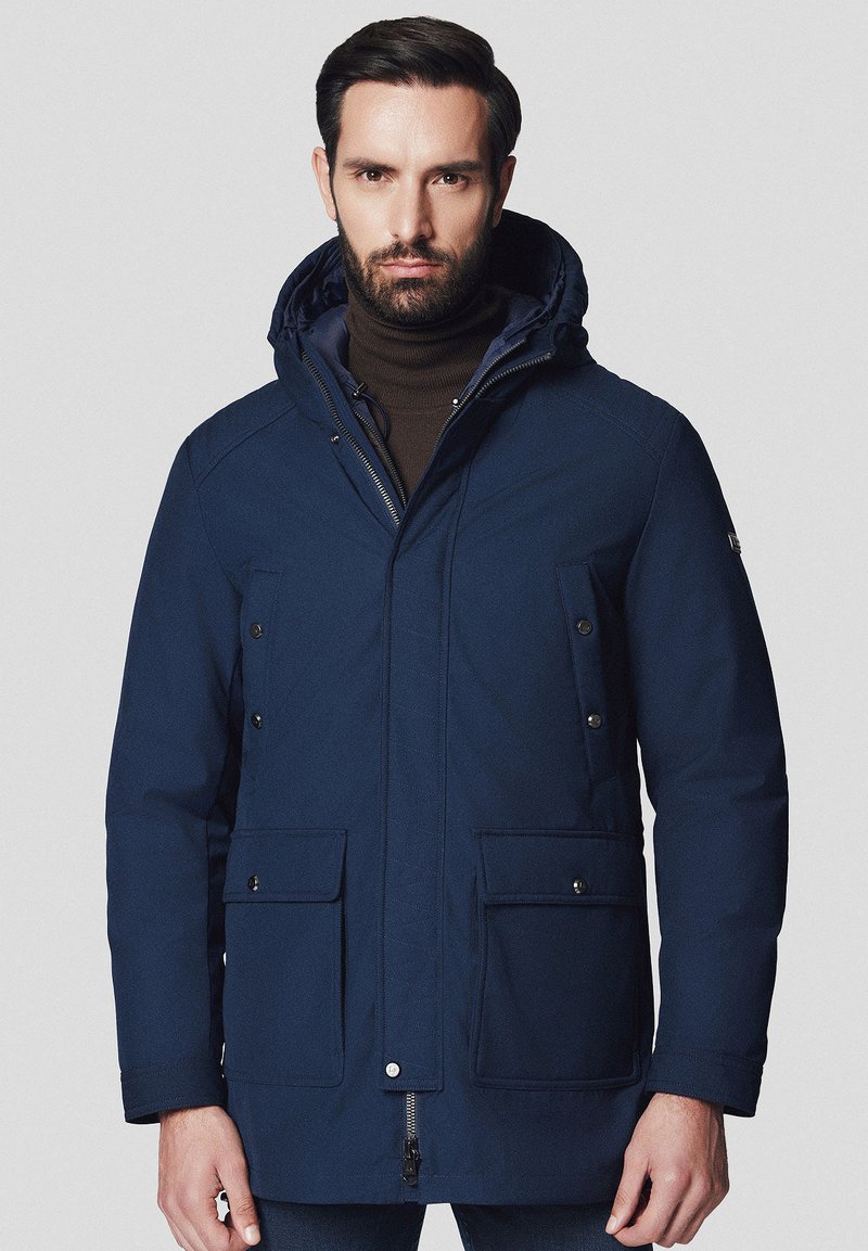 Granatowa parka, wyposażona w kaptur, zamek błyskawiczny, dwie przednie kieszenie z klapami oraz teksturowany materiał. Uniwersalny design na chłodniejsze dni.