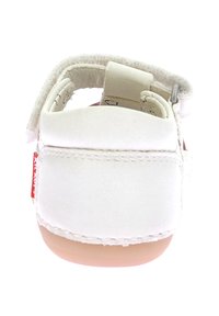 Sandalo bianco in pelle con un retro morbido e arrotondato, cinturino in Velcro e suola in gomma rosa. Presenta cuciture lungo la cucitura e un'etichetta rossa.