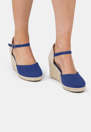 Blue canvas wedge shoes with a jute rope sole and ankle strap. The shoes feature a rounded toe and textured heel.