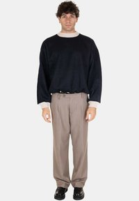 Maglione a maglia blu navy con colletto crema, abbinato a pantaloni plettati marroni chiari e scarpe nere. Tessuto texture, vestibilità comoda.