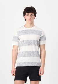 T-skjorte med korte ermer i lys grå med mørkegrå horisontale striper, rund hals, mykt materiale, avslappet passform, kombinert med svarte shorts.