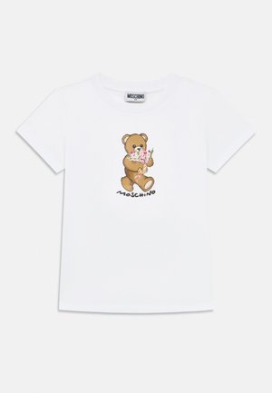Camiseta blanca de manga corta con un oso de peluche sosteniendo flores rosas y la palabra "Moschino" impresa debajo del oso en la parte frontal.