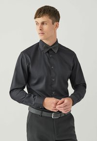 Czarna koszula z dopasowanym krojem, z guzikami z przodu, długimi rękawami i dopasowaną, wzorzystą muszką. Gładki materiał i elegancki design.
