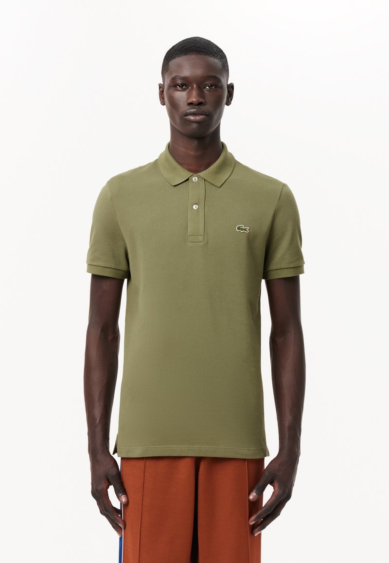 Olivgrön polo skjorta med mjuk textur, korta ärmar, treknappssläpp och broderad logotyp på vänster bröst.